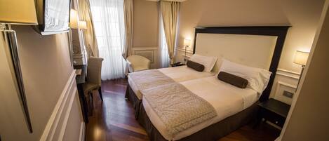 Una habitación de hotel con una cama grande, mesitas de noche, una silla y un televisor.