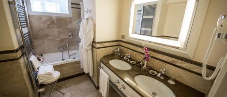 Un baño moderno con dos lavamanos, un espejo grande, una bañera y una ducha.