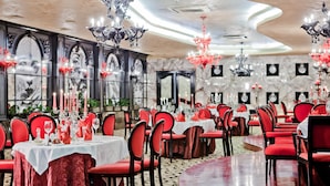 A banquet hall with round tables, red chairs, and chandeliers. - Hotel Maritza (Plovdiv)