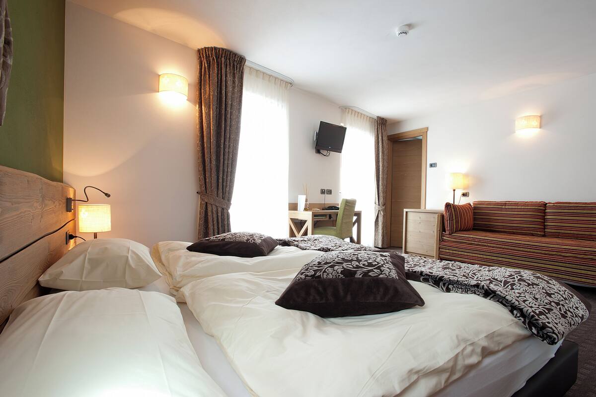 Una habitación de hotel con una cama, un sofá, un escritorio y una televisión.