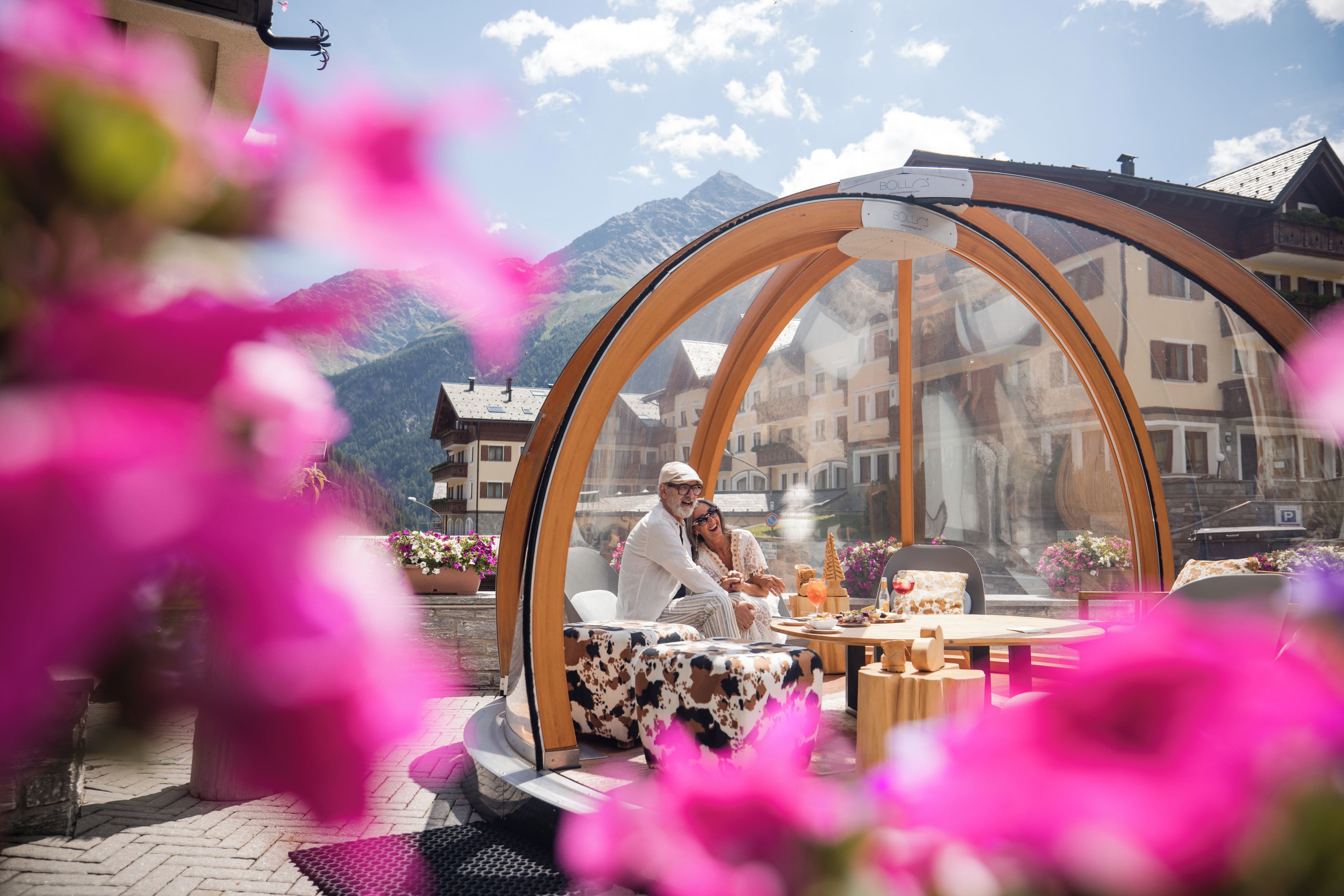 A couple dining in a transparent dome structure with a mountain view.