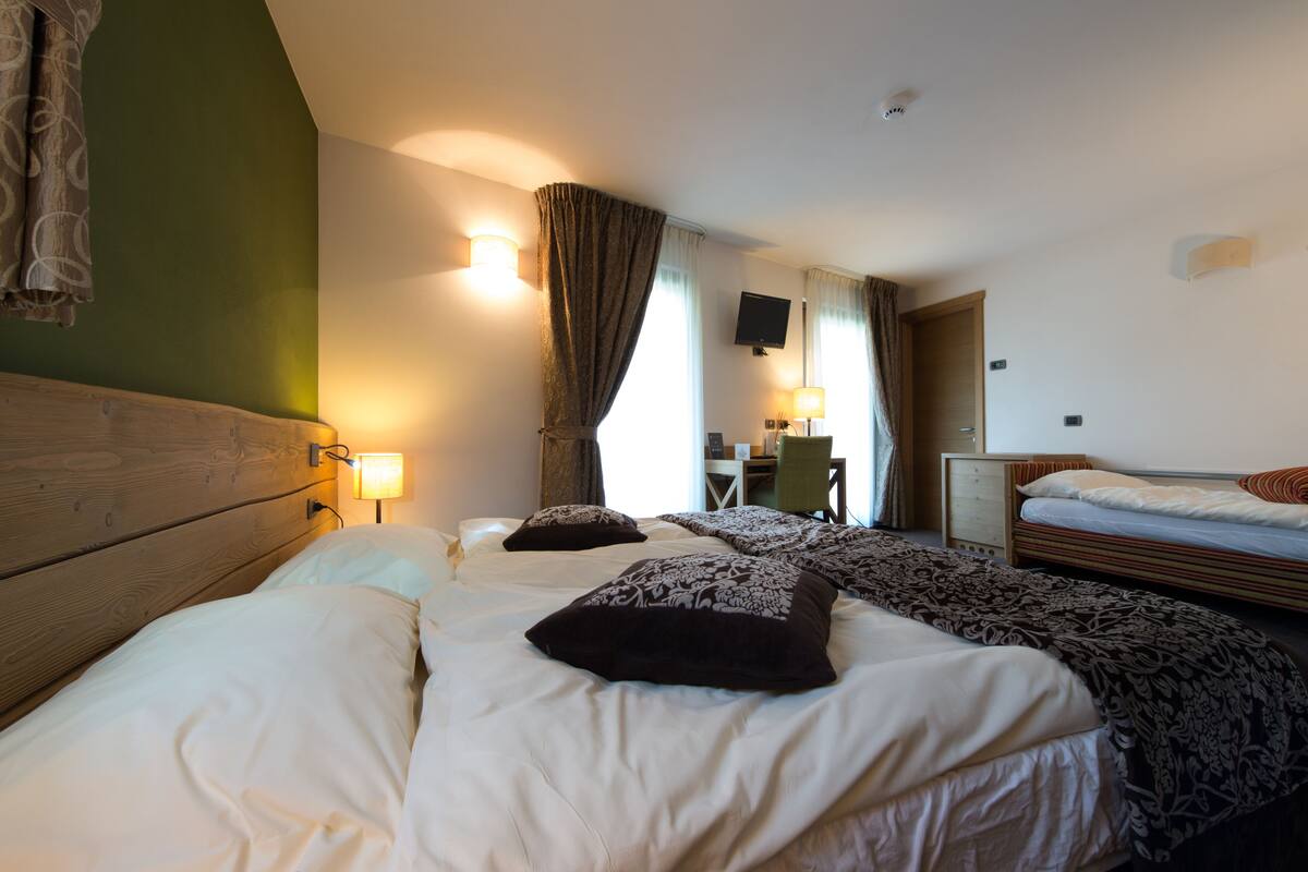 Habitación de hotel con dos camas, un escritorio, una silla y un televisor.