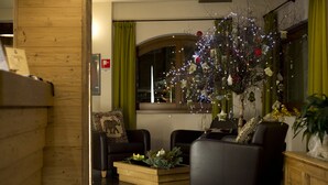 A cozy living room with two leather sofas, a wooden coffee table, and a Christmas tree adorned with lights and ornaments. - Vedig (Valfurva)