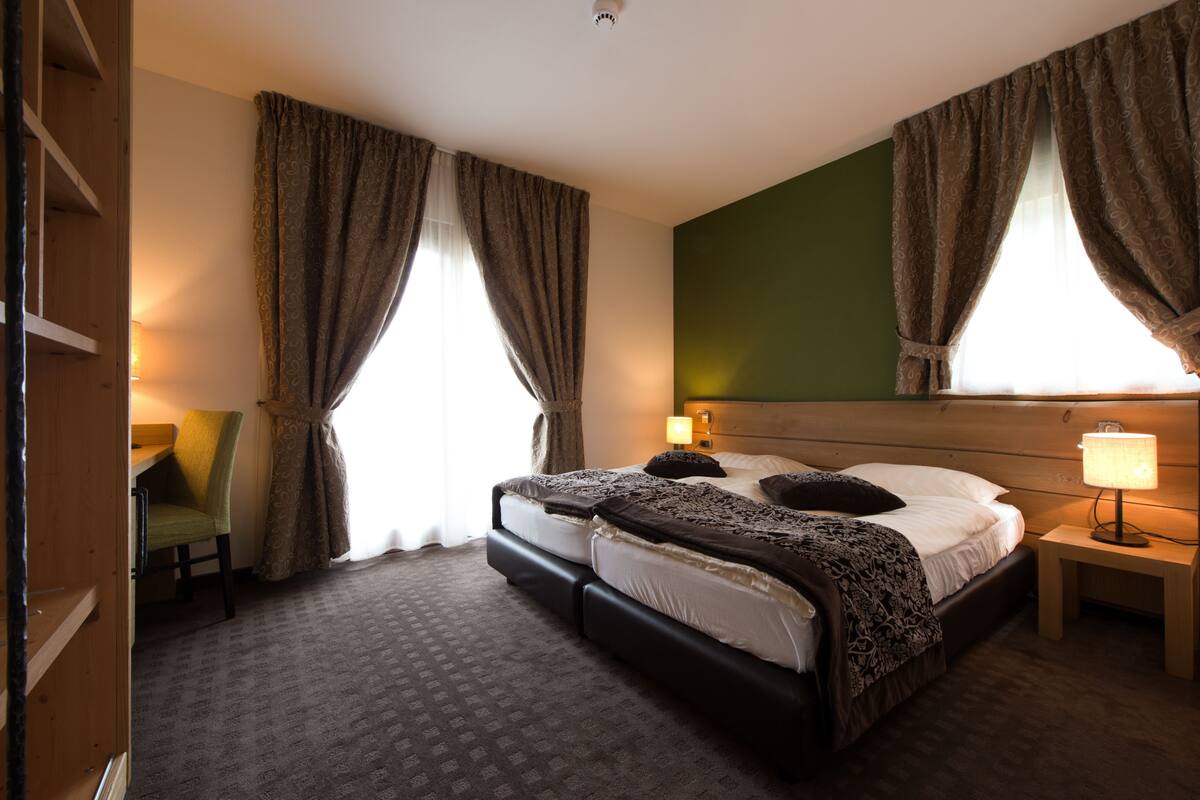 Habitación de hotel con cama doble, dos lámparas de noche, una silla y un escritorio.