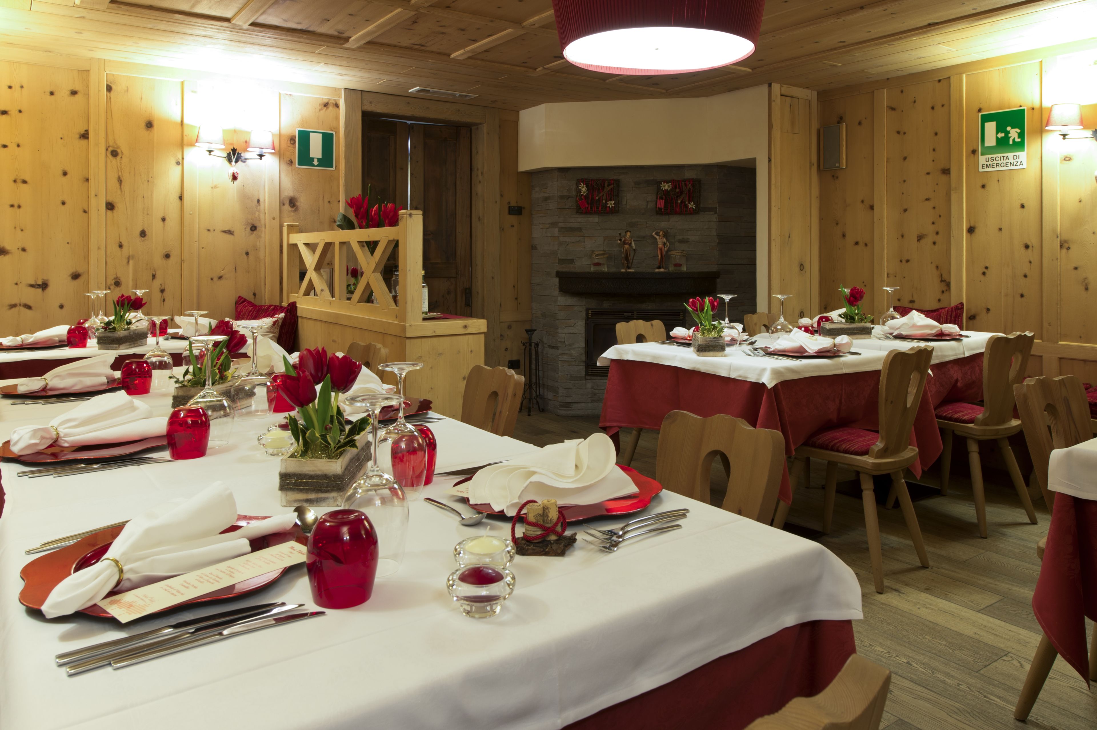 A dining area with tables set for a meal, a fireplace, and wooden walls.