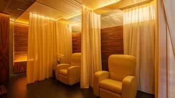 A room with three leather chairs, wooden panel walls, and curtains.