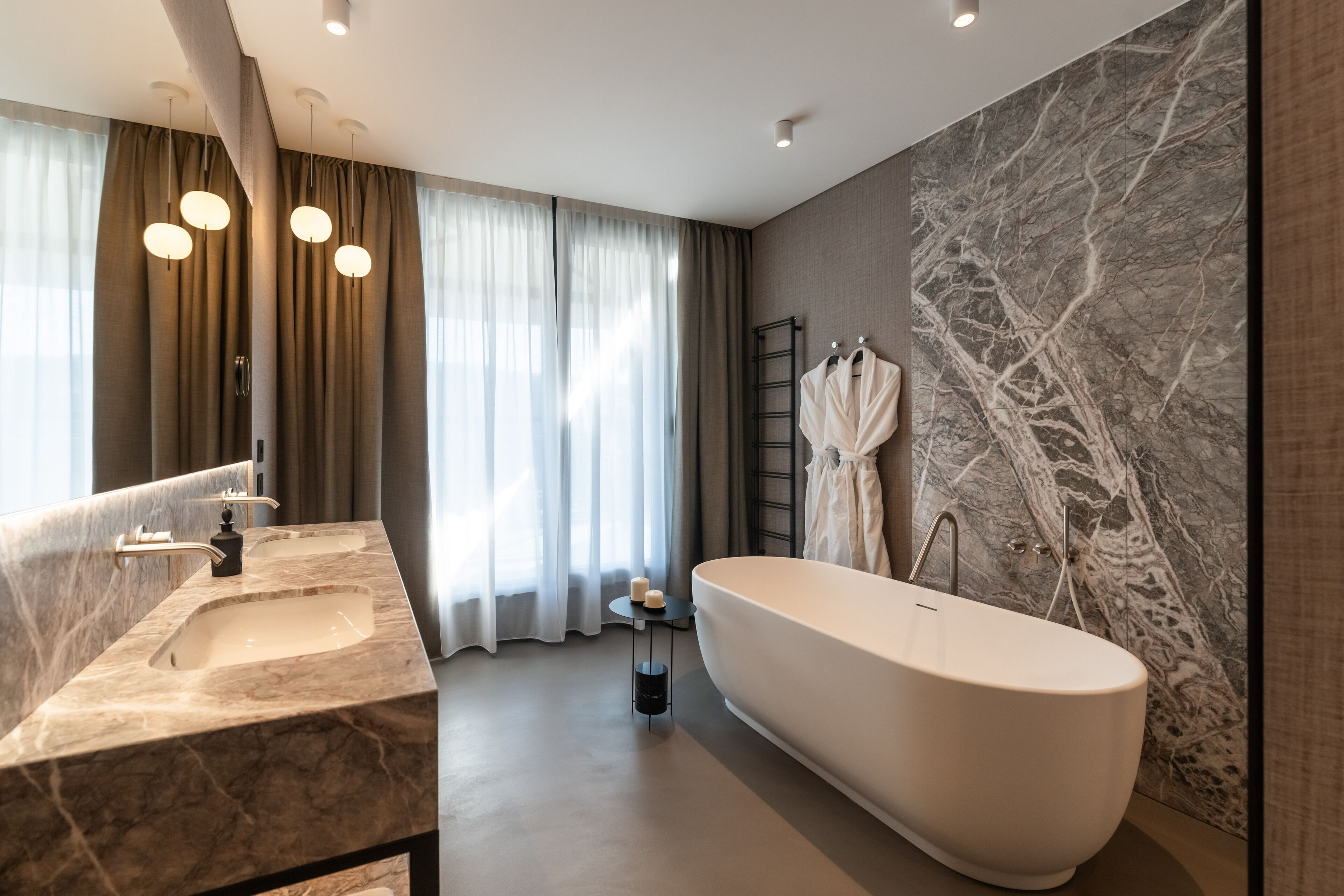 Un baño moderno con una bañera independiente, lavamanos dobles y un tocador de mármol.