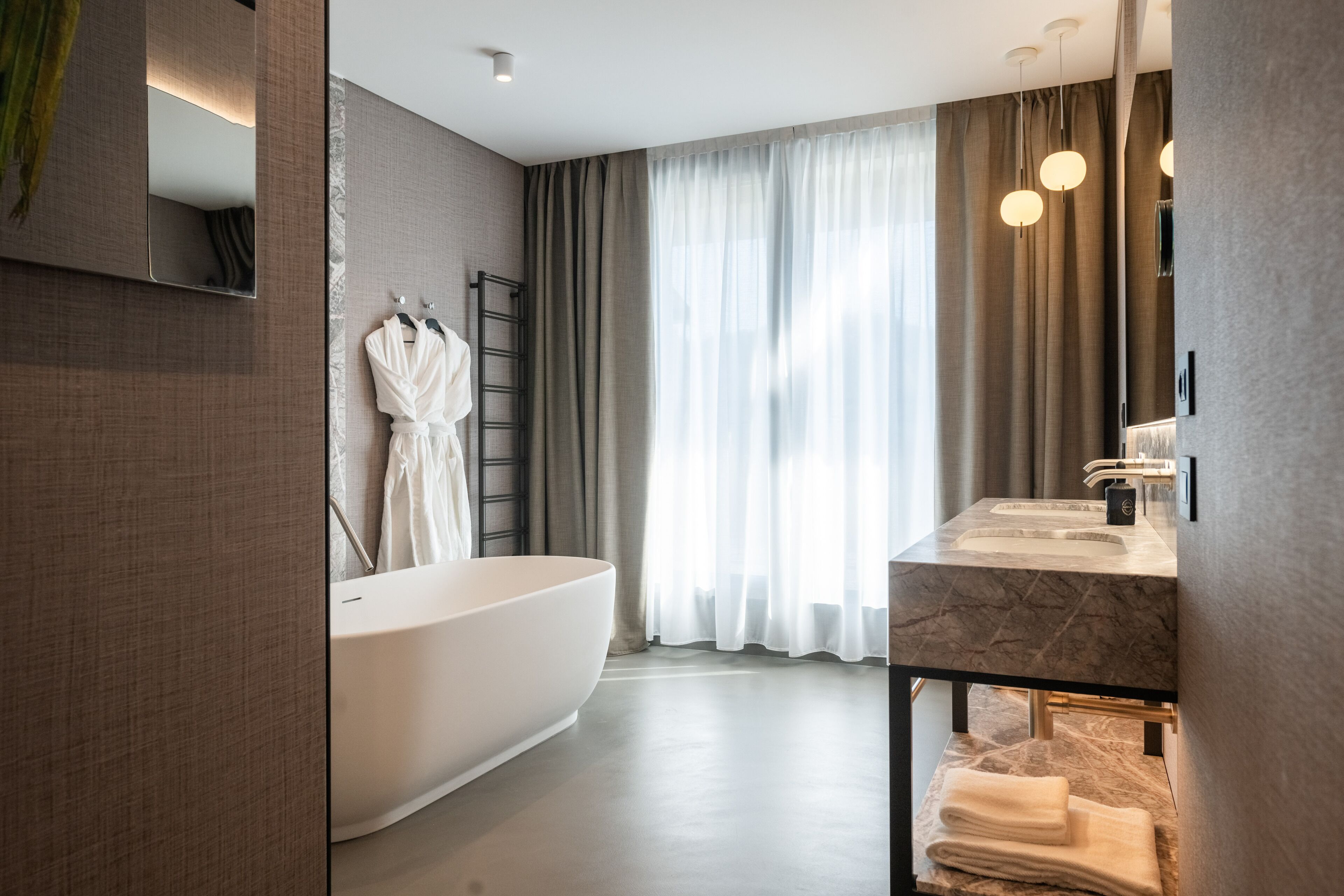 Un baño moderno con una bañera independiente, un tocador con encimera de mármol y un espejo grande.