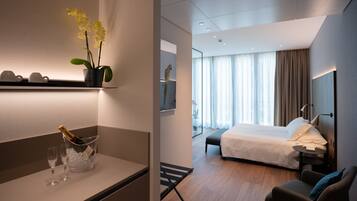 Una camera d'hotel moderna con un letto, un comodino e una piccola zona relax.