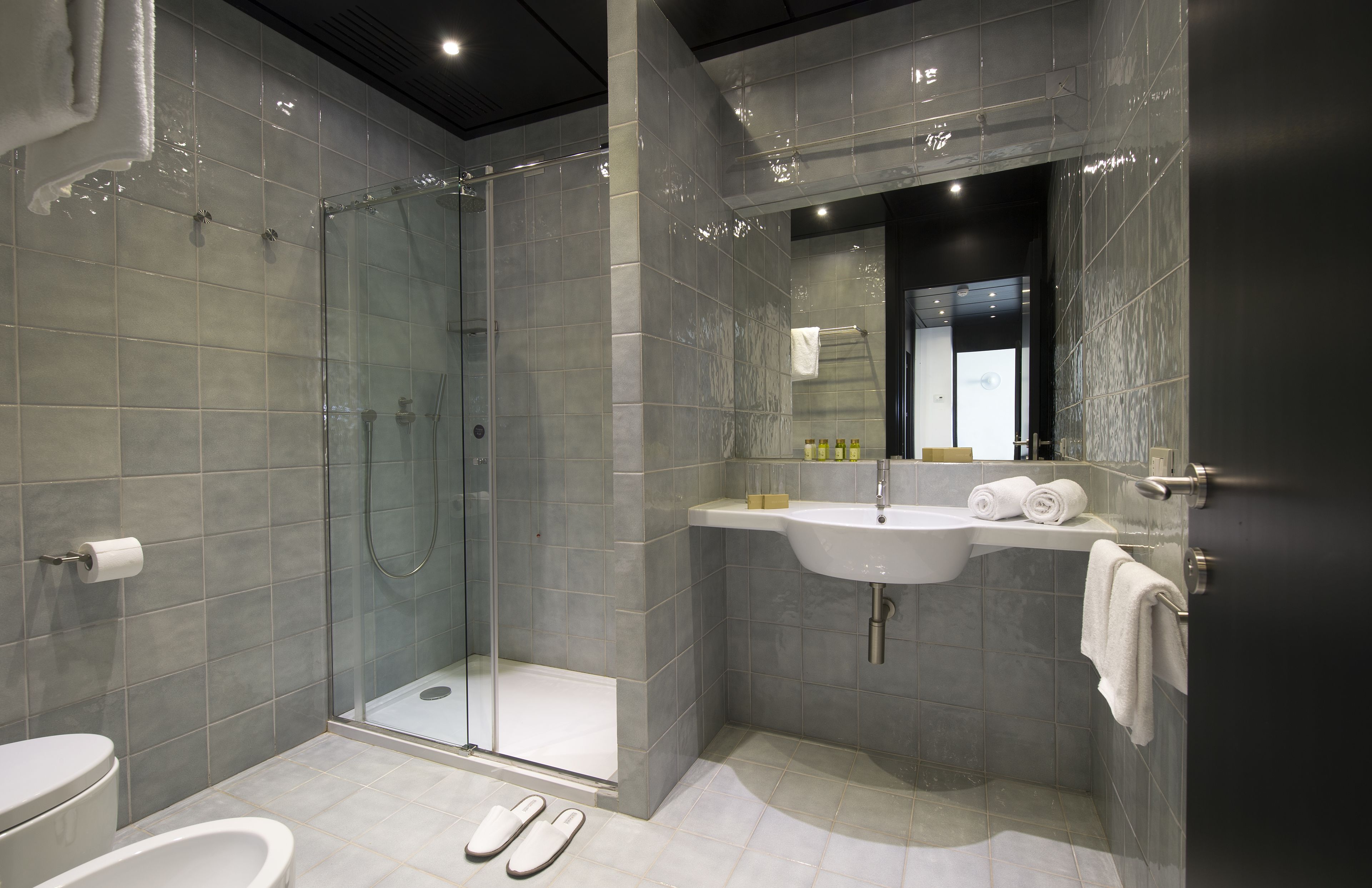 Un baño moderno con ducha de vidrio, lavamanos e inodoro.