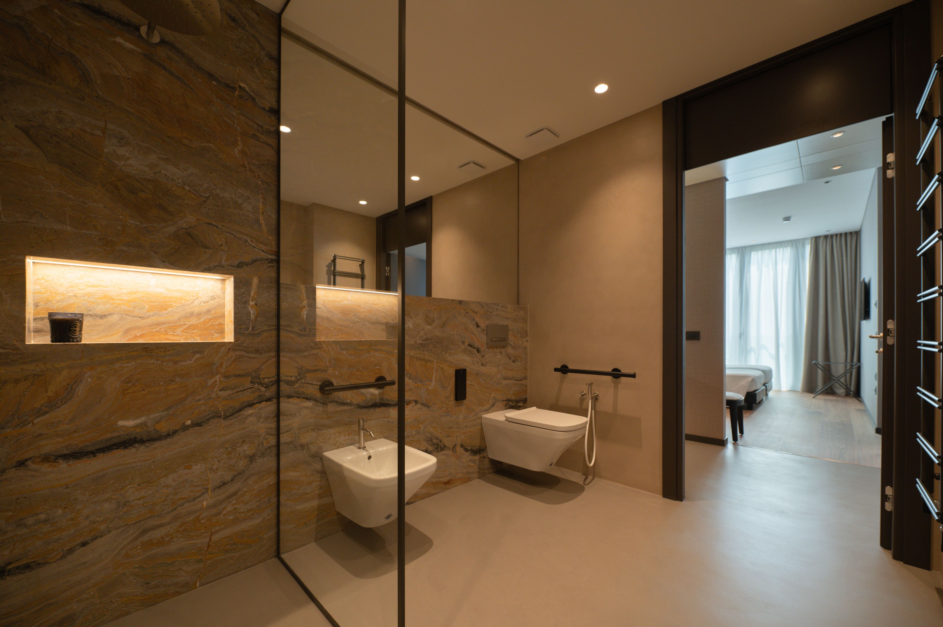 Une salle de bain moderne avec un mur en marbre, un lavabo sur colonne et une baignoire.