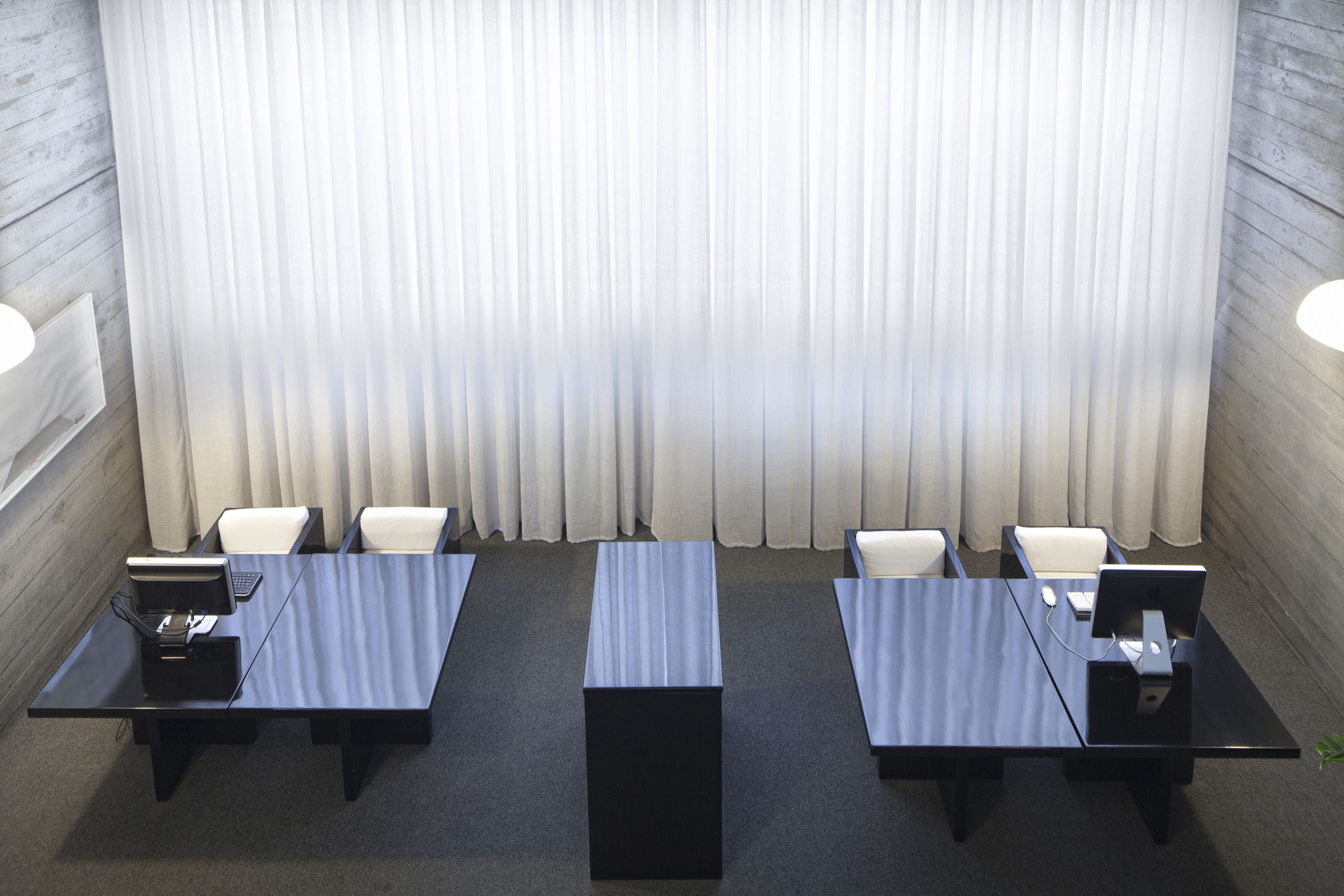 A conference room with a long table, four chairs, and two computer stations.