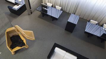 Quarto de hotel com escrivaninha, cadeiras, sofá, mesinha e cama para animais de estimação.