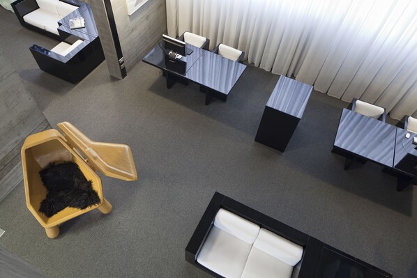 A hotel room with a desk, chairs, a sofa, a small table, and a pet bed.