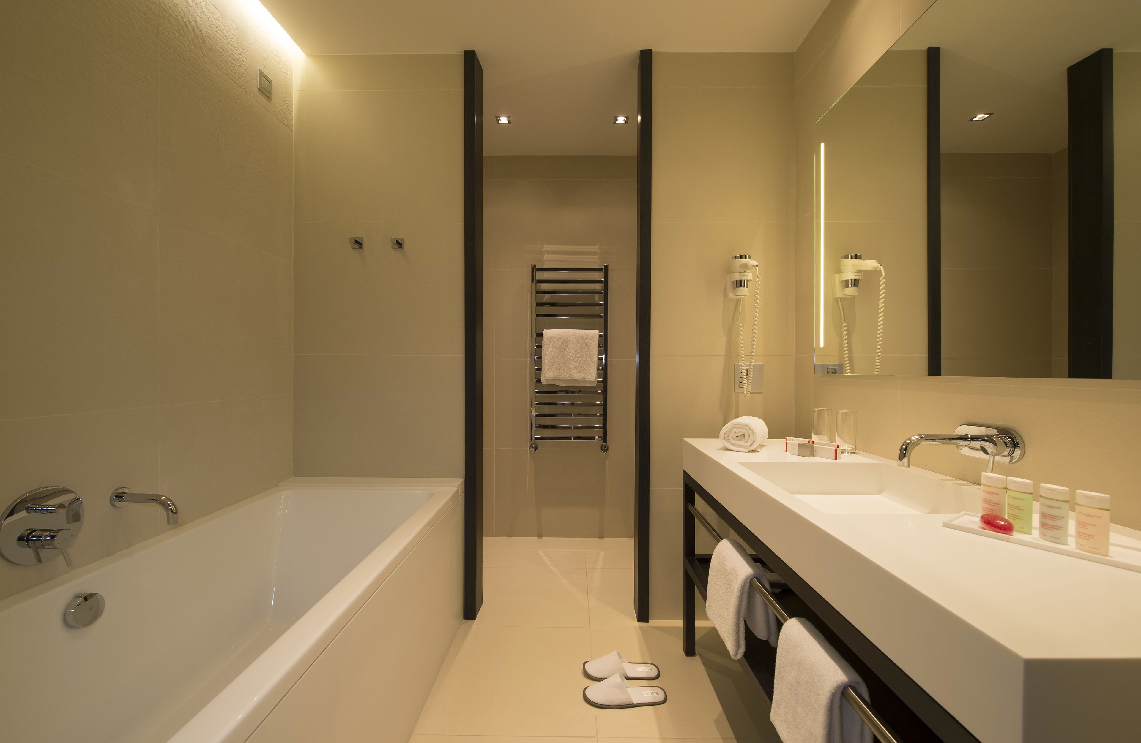 Un baño moderno con bañera, ducha, tocador con espejo y un perchero para toallas.