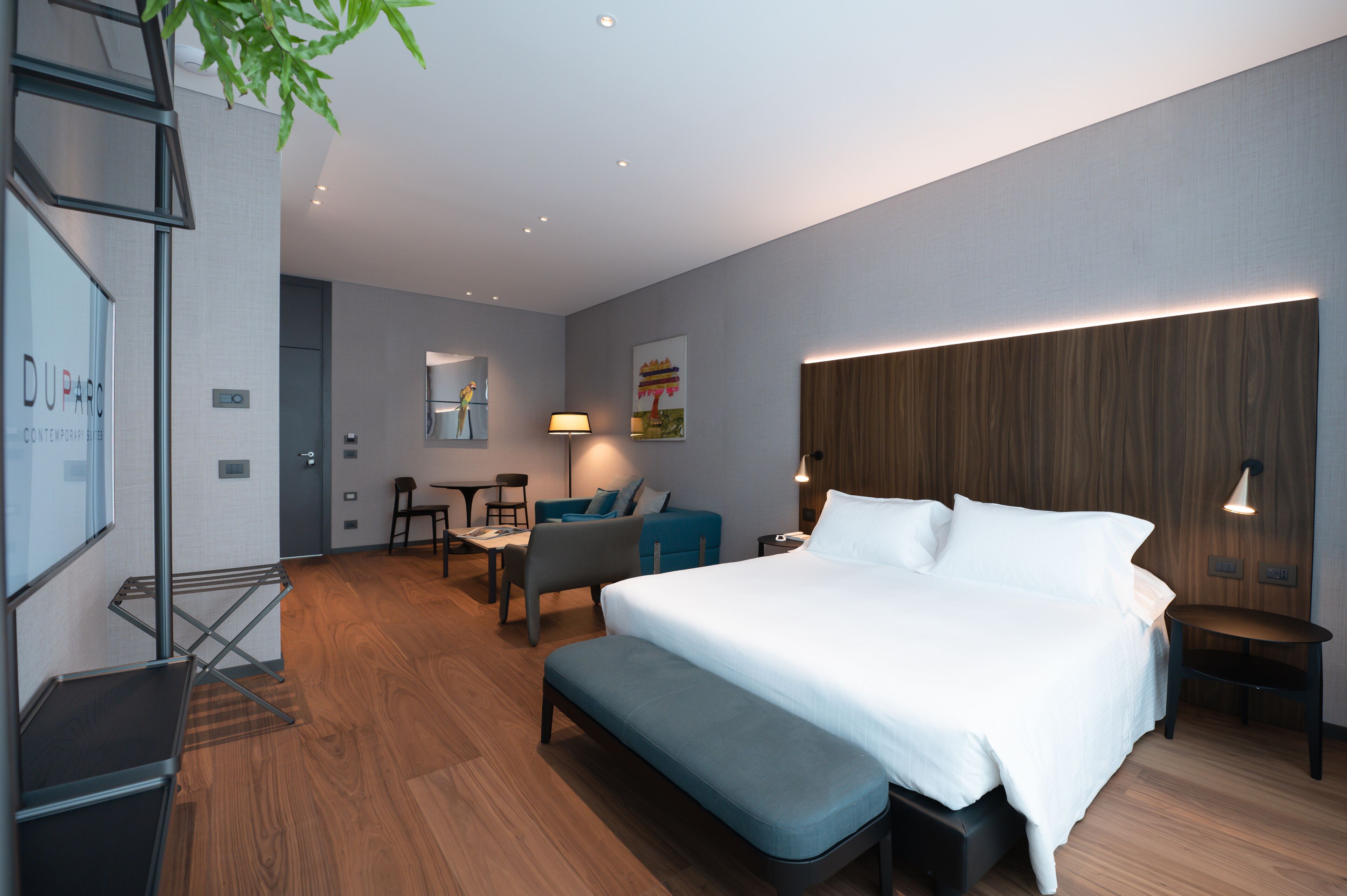 Een moderne hotelkamer met een groot bed, een zithoek met een bank en stoelen, een kleine tafel en een bureau.