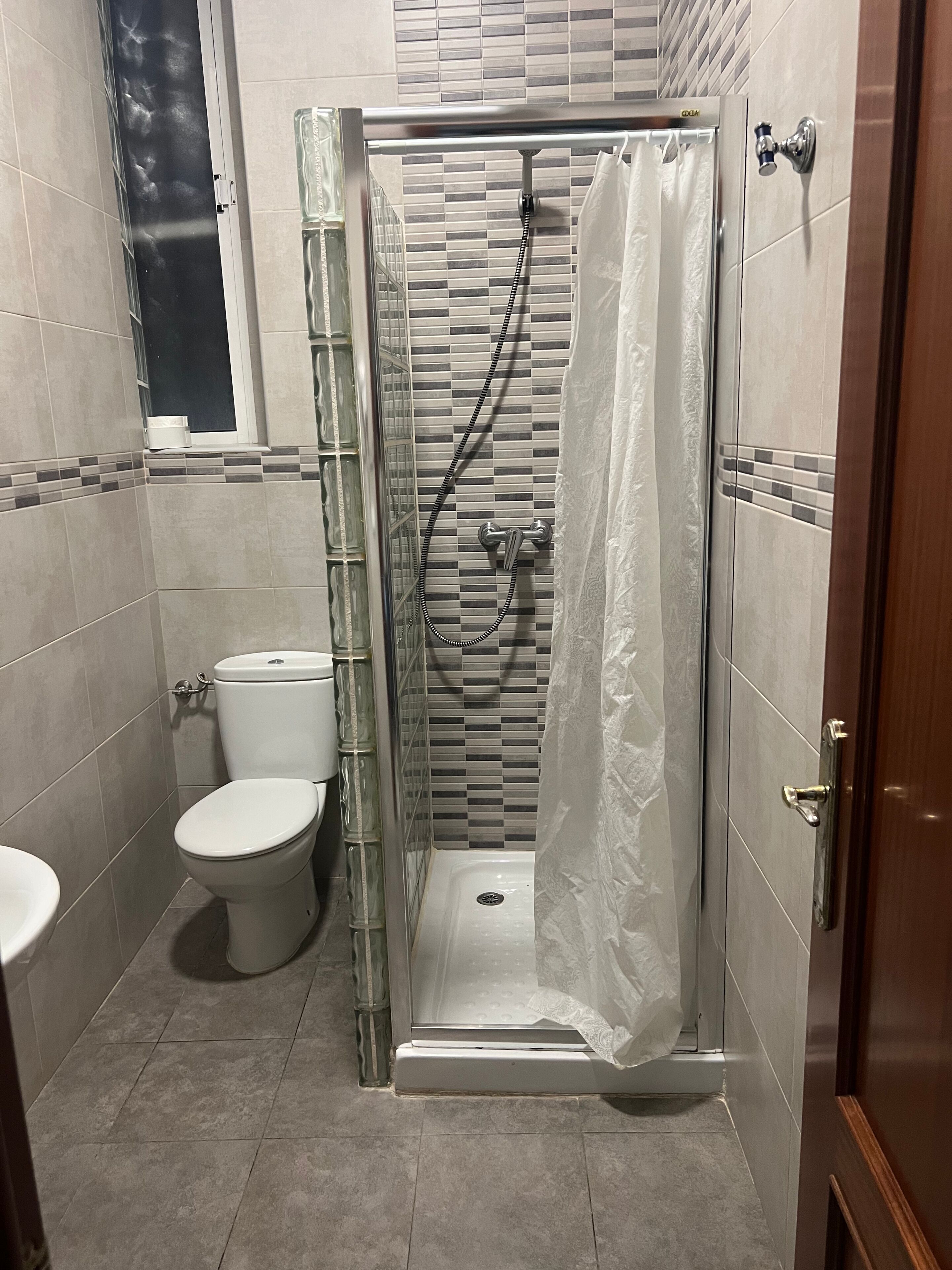 Un baño con ducha envuelta en vidrio, inodoro y lavabo.