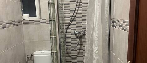 Un baño con ducha envuelta en vidrio, inodoro y lavabo.