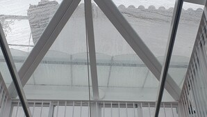 A skylight with a cross-bracing structure, a white ceiling, and a view of a building outside. - Pensión Catedral (Seville)