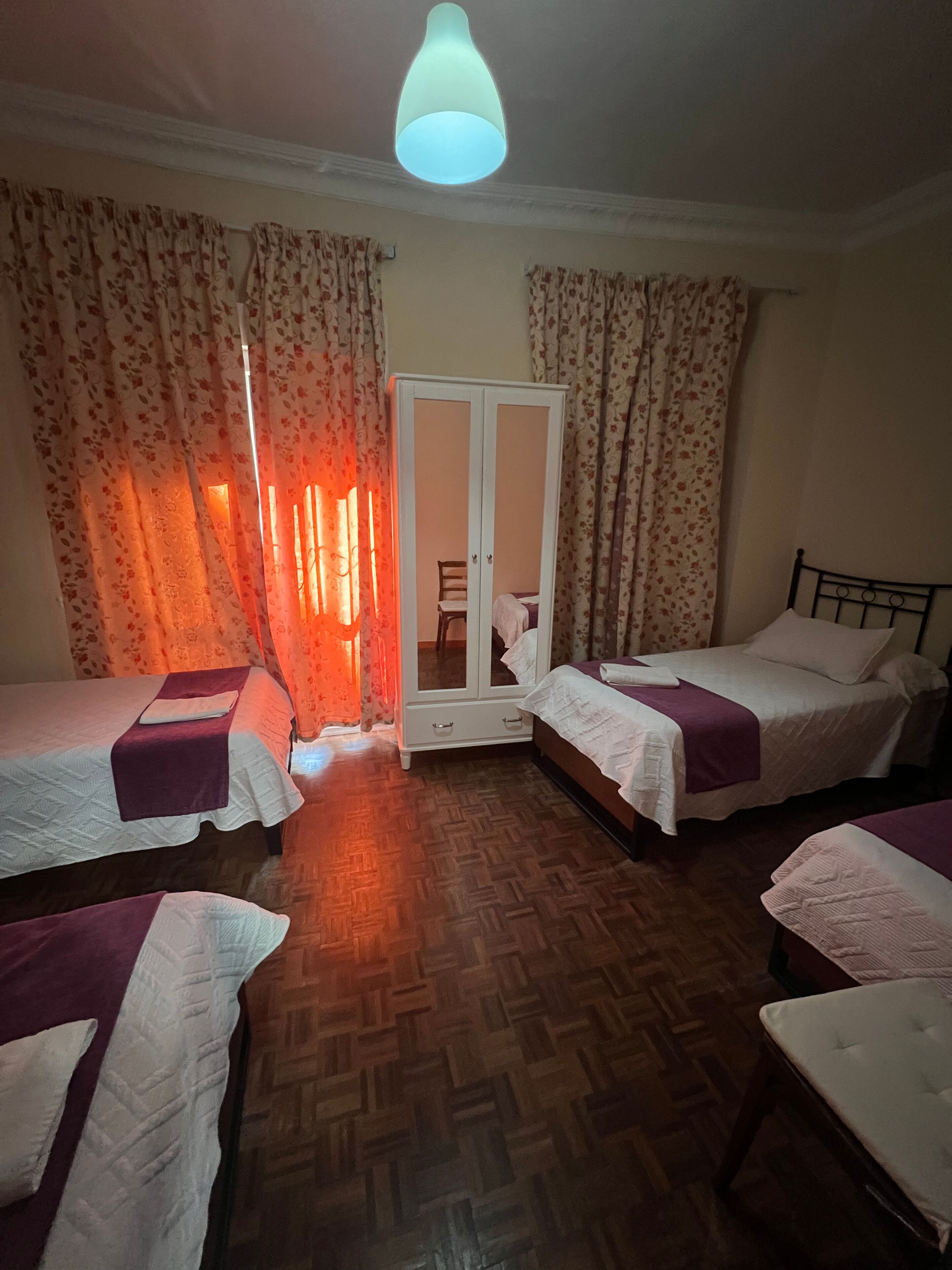 A room with two beds, a wardrobe, and a mirror.