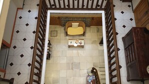 A narrow hallway with a tiled floor, a wooden door frame, and a small shelf with a decorative item. - Pensión Catedral (Seville)
