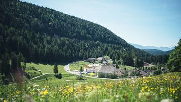 A rural village with houses and a church surrounded by forested hills.