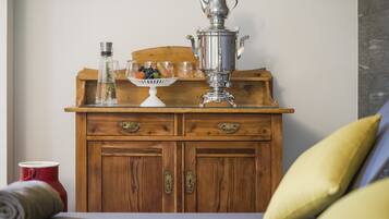 A wooden dresser with two drawers, a metal teapot, and a glass bowl with fruits.