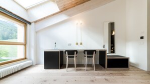 Une chambre moderne avec une lucarne, un bureau noir avec deux chaises et un grand miroir.