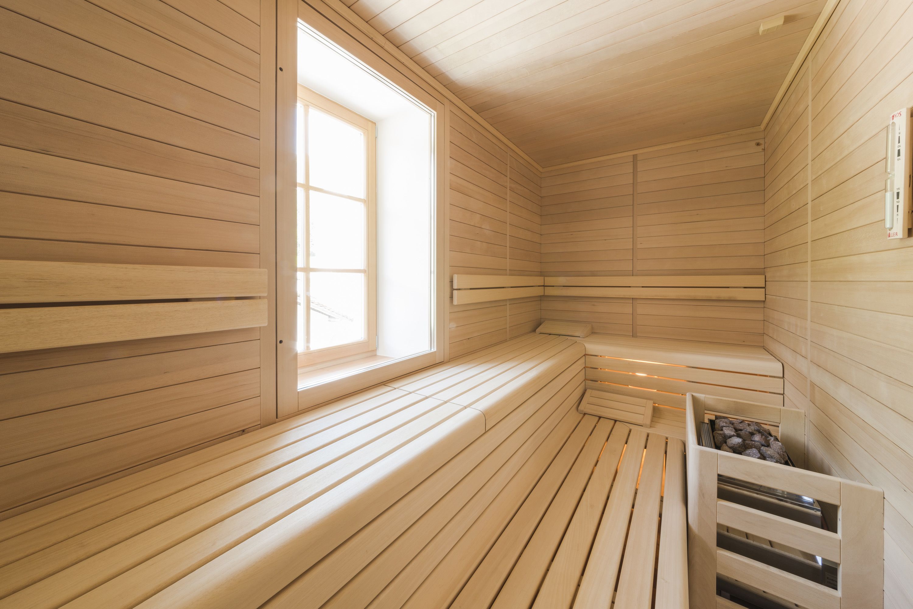 A sauna with wooden benches, a window, and a heater.