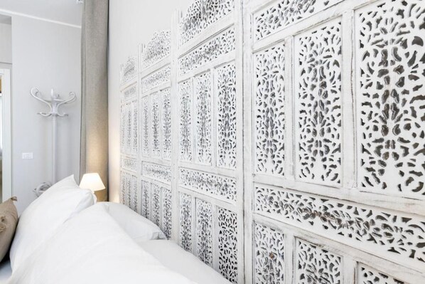 A hotel room with a bed, a nightstand, a lamp, and a decorative wall panel.