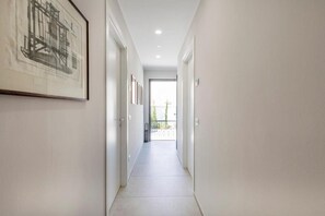 A narrow hallway with white walls, a tiled floor, and a framed architectural drawing on the left. - I Bravi (Cormano)