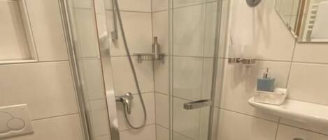 Un baño moderno con ducha de vidrio, un lavabo blanco y un inodoro.