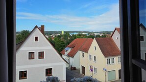 Vue depuis l’intérieur d’un bâtiment, donnant sur une rue bordée de maisons, avec un panneau indiquant la limite de vitesse et un panneau interdisant le stationnement.