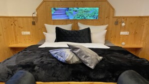 Un lit recouvert d’un tissu de velours noir, avec des oreillers blancs et noirs, et une tête de lit capitonnée.