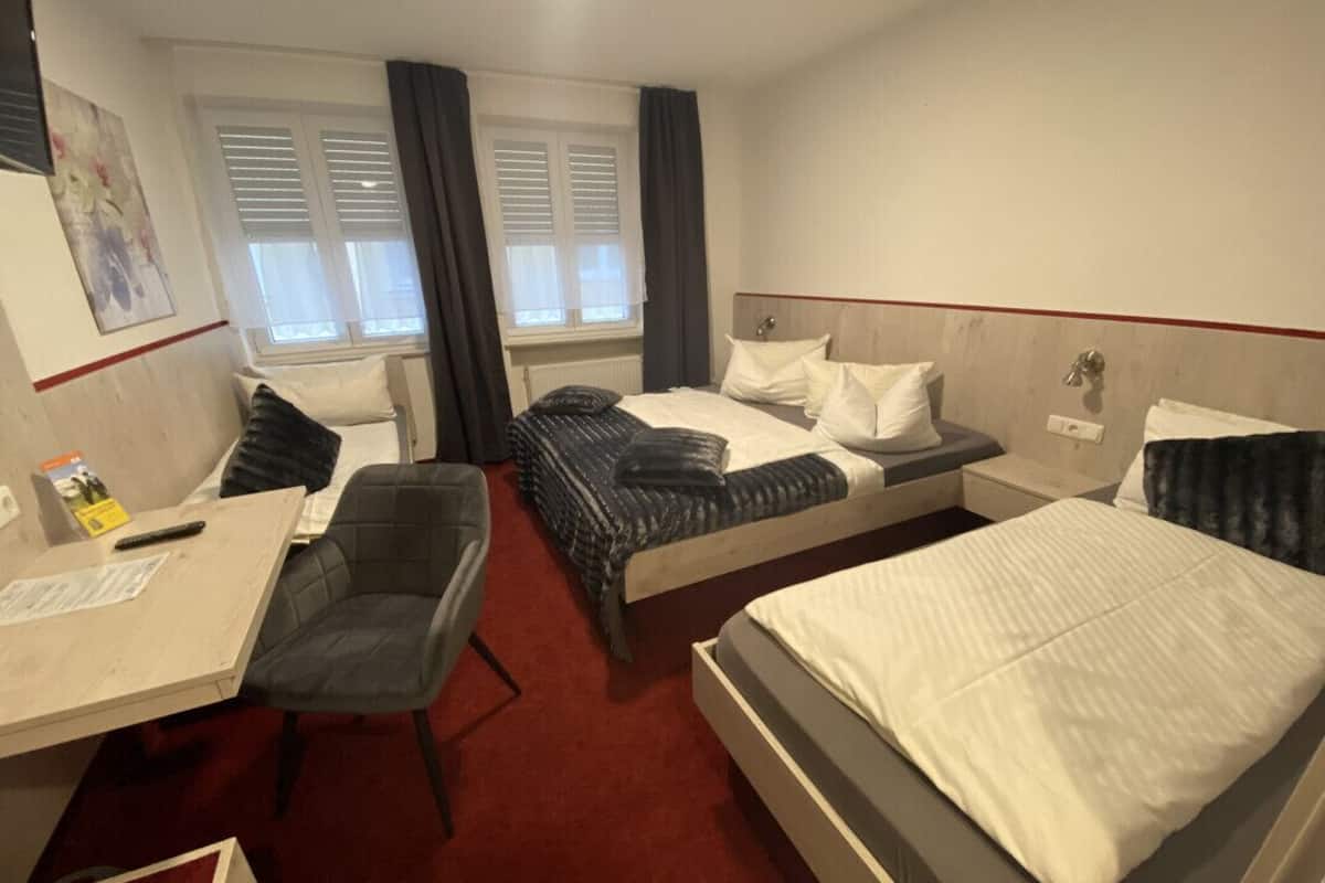 A hotel room with two beds, a desk, and a chair.