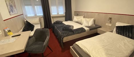 A hotel room with two beds, a desk, and a chair.