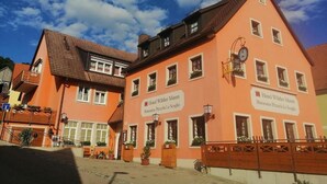 Un bâtiment européen traditionnel, avec des enseignes indiquant un hôtel appelé « Hotel Wilder Mann » et un restaurant.