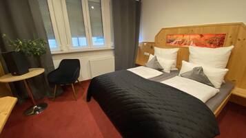 A hotel room with a bed, a desk, a chair, and a window with curtains.
