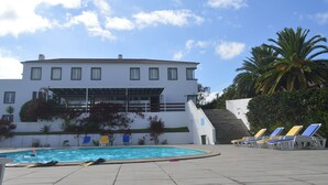 A pool area with lounge chairs, a building with a white facade, and a staircase leading up to the building. - Apartamentos Turísticos Nossa Senhora da Estrela (Lagoa)