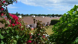 A residential area with a tiled roof, a garden with green foliage, and a clear sky. - Apartamentos Turísticos Nossa Senhora da Estrela (Lagoa)