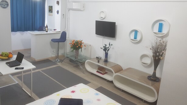 Een moderne woonkamer met een flatscreen televisie, een glazen salontafel en een bank.