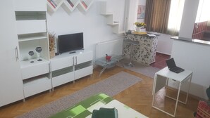 Een moderne woonkamer met een flatscreen televisie, een klein barretje en een eethoek met een tafel en stoelen.