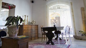 A spacious room with a high wooden ceiling, a large arched doorway, and a dining area with a table and chairs. - B&B La Via della Giudecca (Syracuse)