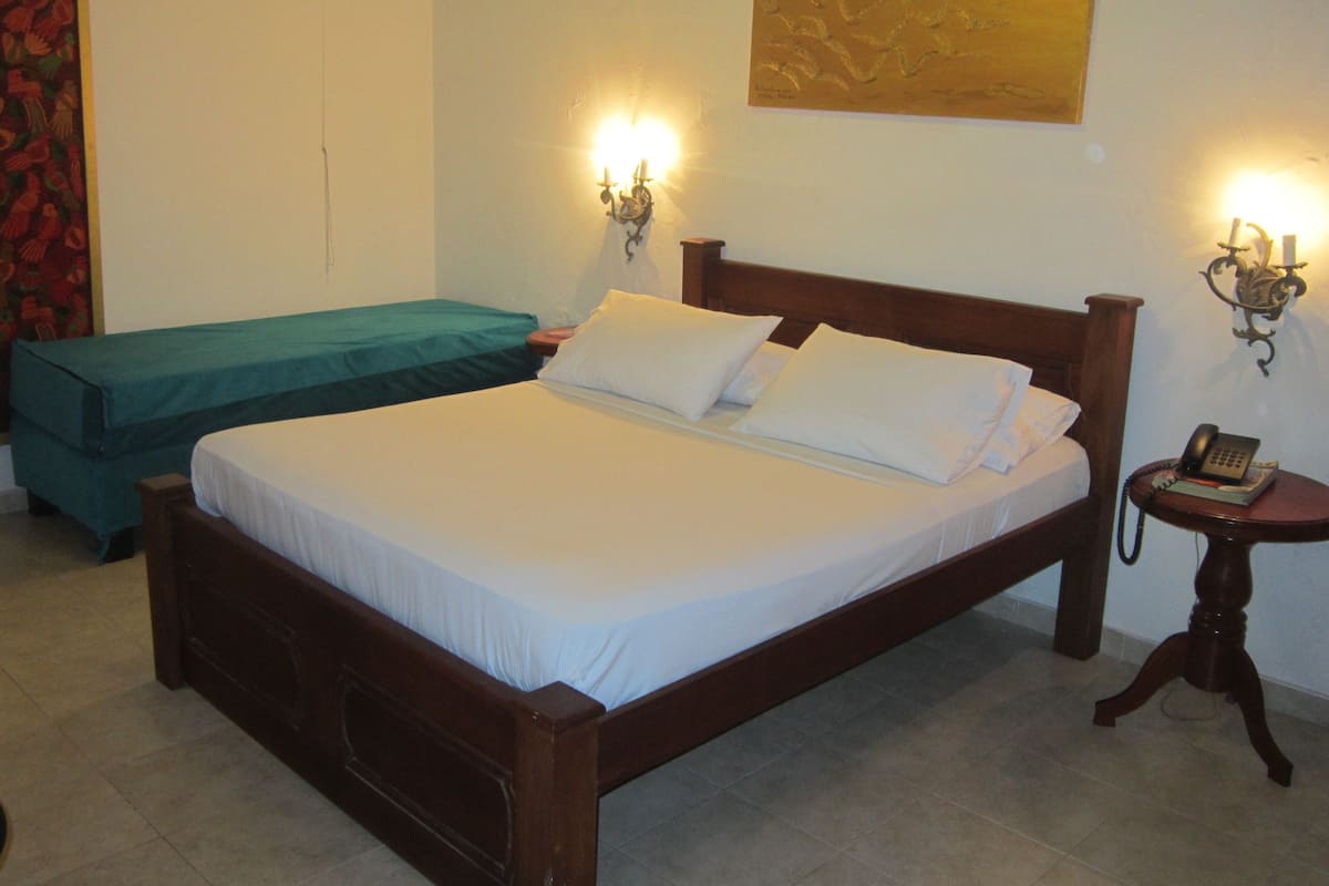 A double bed with white linens, a wooden headboard, and two bedside tables with lamps.