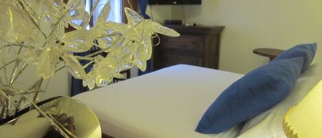 A hotel room with a bed, a TV on a stand, and a decorative plant.