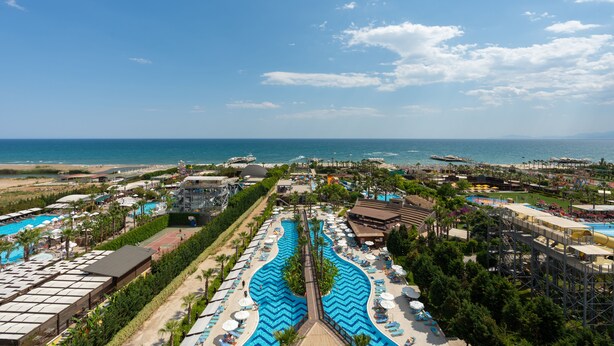 Un resort con piscina centrale, diverse piscine più piccole e vista sulla spiaggia.