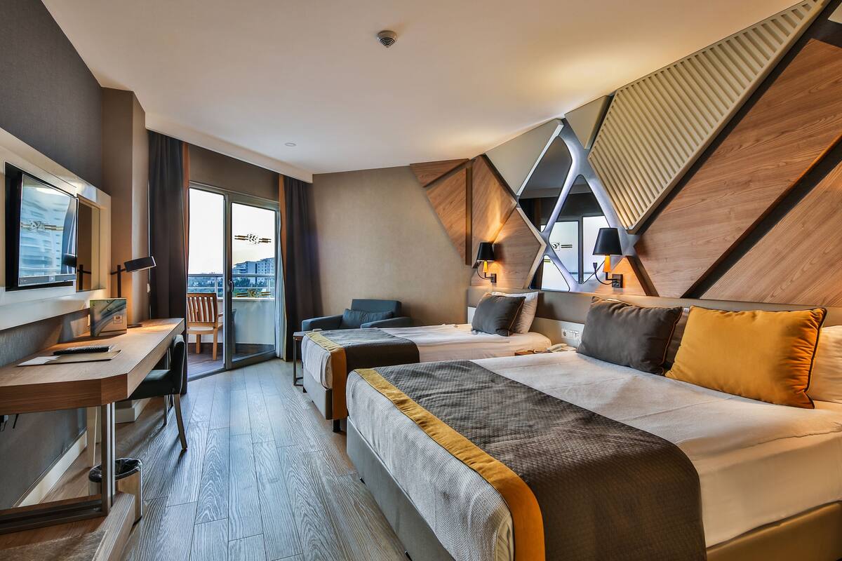 Een hotelkamer met een bed, een bureau, een stoel en een groot raam.