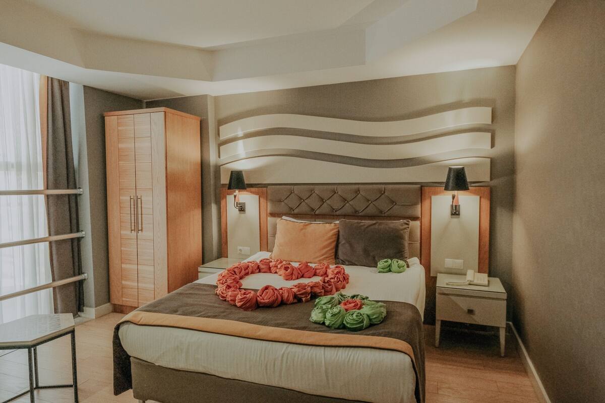 Een hotelkamer met een bed, een kledingkast, bedlampen en een nachtkastje.