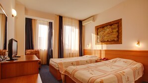 Ein Hotelzimmer mit zwei Betten, einem Schreibtisch, einem Stuhl und einem Fernseher.