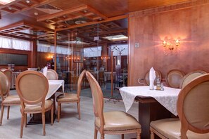A restaurant interior with wooden paneling, glass partitions, and tables set with white tablecloths. - Central Plaza Hotel (Sofia)